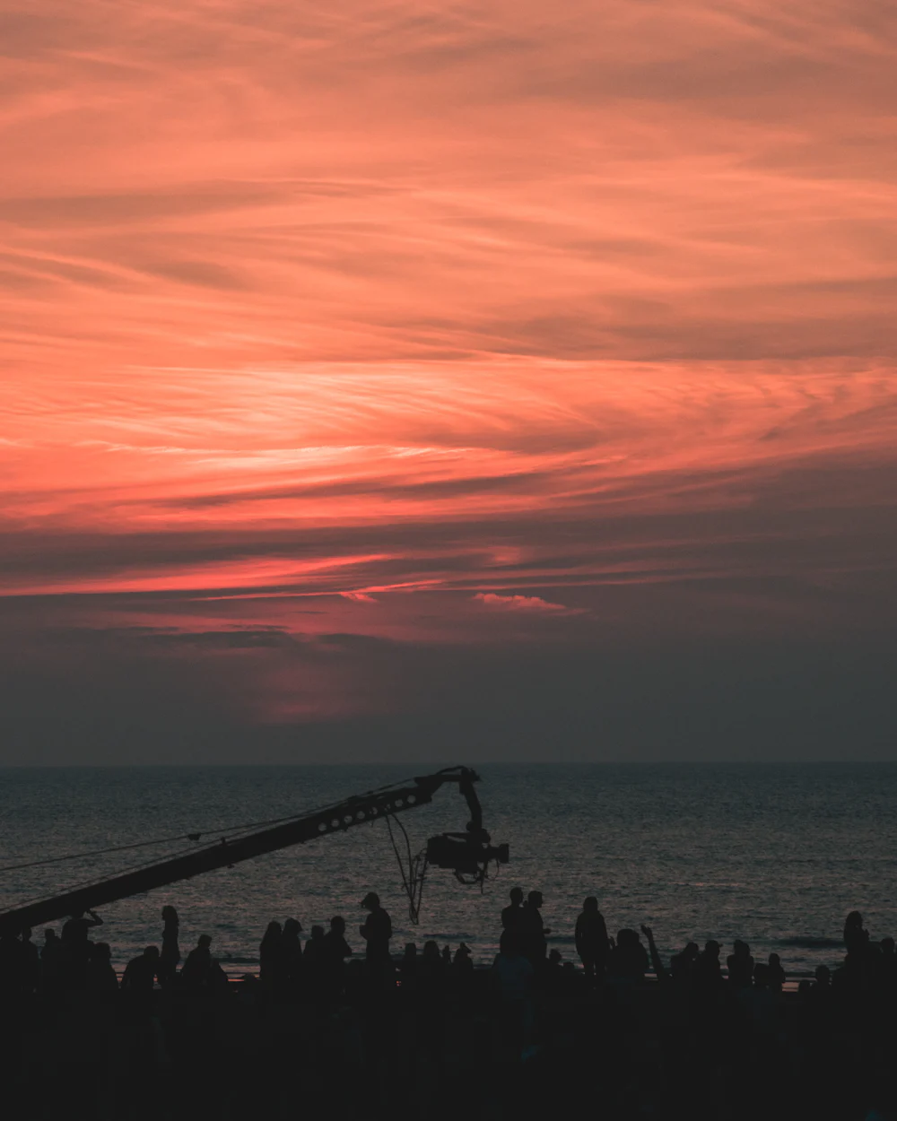 Film crew silhouetted on a beach at sunset